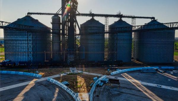 Drone photo of steel silos and a process tower backlit by the sun