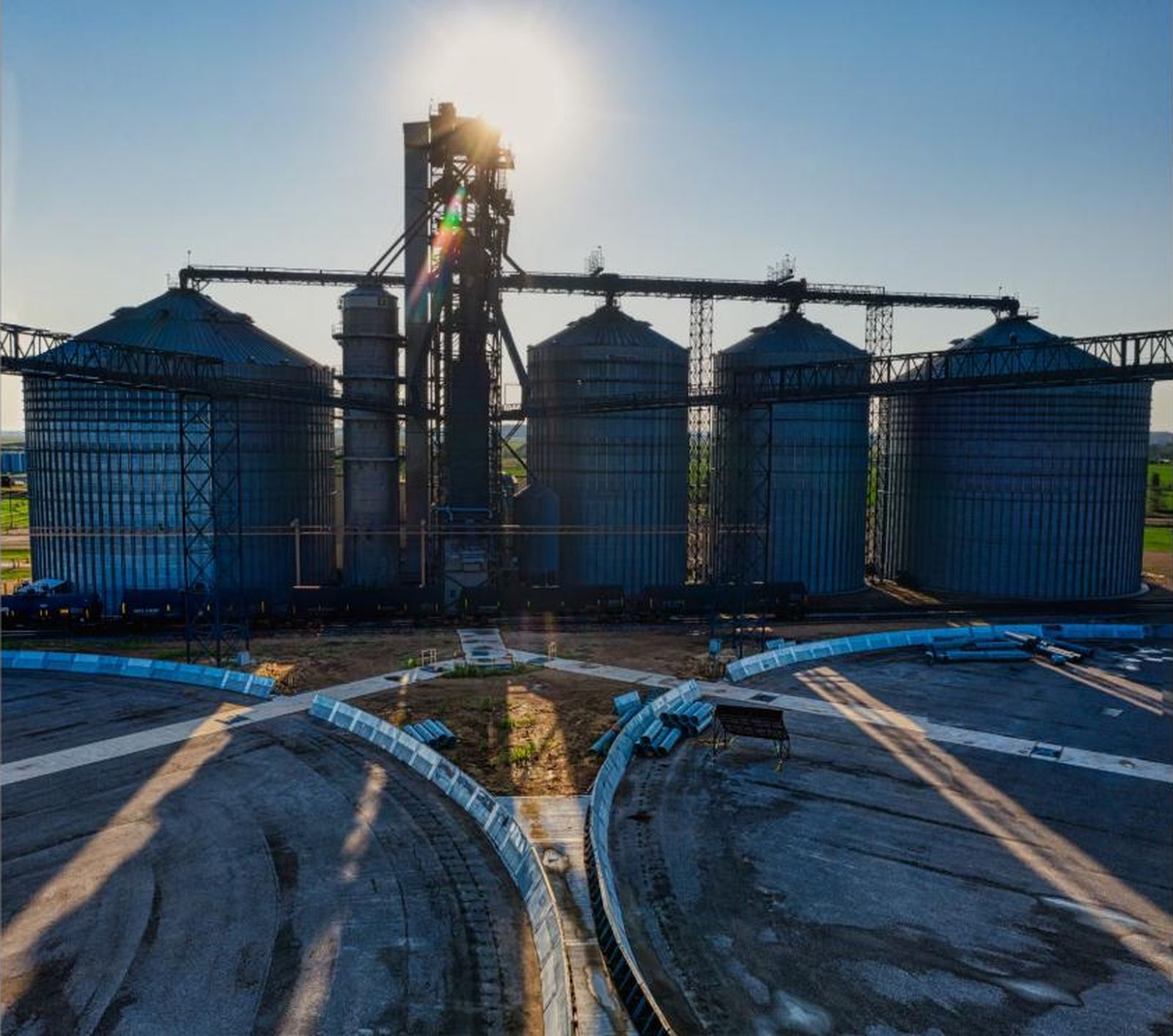 Drone photograph of steel silos and a process tower at a grain and ingredient facility, backlit by the sun — the setting for digital twin manufacturing and predictive maintenance